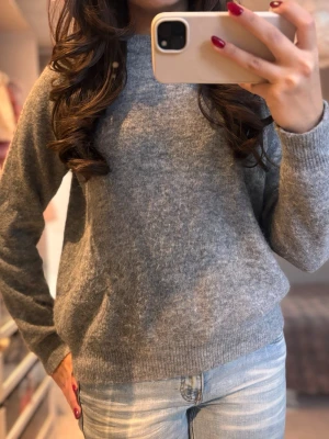 Grå stickad tröja med rund hals - Mysig grå stickad tröja med rund hals och långa ärmar. Perfekt att slänga på sig när det är kyligt ute. Tröjan har en enkel design och ribbade muddar vid ärmslut och nederkant. Passar dig som gillar en klassisk och avslappnad stil. (Säljer både en i storlek S och M)