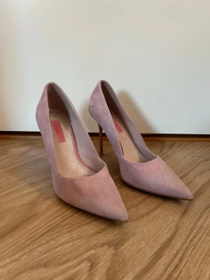 Rosa pumps med spetsig tå - Säljer ett par snygga ljusrosa pumps från Topshop med spetsig tå och hög klack. Skorna är i mjuk mocka och har en stilren design som ger en elegant vibe. Perfekta för dig som vill ha en feminin och trendig look. Finns fläckar på skorna som syns i bilderna. Går säkert bort om man gör rent dom! Skriv för fler bilder. 