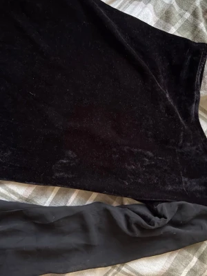 Svart sammetströja från KappAhl - Säljer en svart långärmad tröja från KappAhl i mjuk sammet. Tröjan har en enkel, rak form och är helsvart utan mönster eller detaljer. Perfekt för dig som gillar stilrena plagg med lite lyxig känsla.