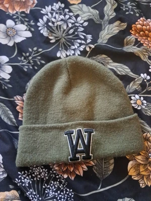 Fin grön mössa - Grön mössa med ett stort "W" broderat på framsidan. Mössan har en ribbstickad kant. Från Stadium.   Skickas via posten men köpare står för frakten. Vid övriga frågor skicka gärna meddelande.  Lämnar självklart god omdömen om köparen gör det.  Kolla in mina andra annonser!