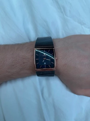 Klocka - En helt ny klocka med mörkblå urtavla och roséguldfärgat hölje, med ett mörk blått mesh-armband. 