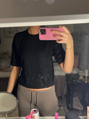 Svart stickad t-shirt - Enkel svart stickad t-shirt med rund hals och korta ärmar. T-shirten har en clean look och är gjord i ett mjukt material som känns skönt mot huden. Perfekt för en chill och avslappnad stil.