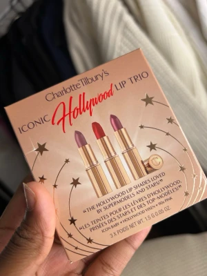 Charlotte Tilbury Iconic Hollywood Lip Trio - Säljer ett set med tre lyxiga läppstift från Charlotte Tilbury i färgerna Icon Baby, Hollywood Vixen och 90s Pink. Alla har snygga guldfärgade hylsor och kommer i en fin presentförpackning med stjärndetaljer. Perfekt för dig som vill ha både nude, röd och rosa nyans.