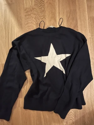 Mörkblå stickad tröja med stjärna - Stockholmsstil Mörkblå stickad tröja med en stjärna i mitten 