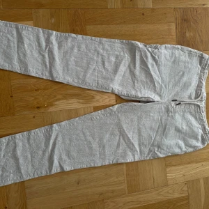 Ljusbeige linnebyxor från Dressmann M - Snygga ljusbeige linnebyxor från Dressmann i storlek M. Byxorna har resår och dragsko i midjan för skön passform samt två bakfickor med knapp. Perfekta för en chill och stilren look under varmare dagar.