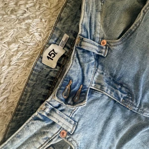 Ljusblå jeans från 157 med raka ben - Snygga ljusblå jeans från 157 med klassisk femficksdesign och raka ben. Jeansen har kopparfärgade nitar och bälteshällor, tillverkade i slitstarkt denim. Perfekta för en avslappnad och trendig look.