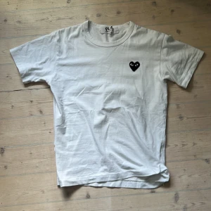 Vit t-shirt Comme des Garçons Play - Vit t-shirt från Comme des Garçons Play med hjärta-trycket på bröstet. Jag säljer då den inte passar mig, den är i Storlek S. Perfekt för dig som gillar stilrena och trendiga plagg. Hör av dig om du har frågor!
