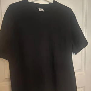 Svart basic t-shirt från Zara - Enkel svart t-shirt från Zara med klassisk rund hals och korta ärmar. Modellen är rak och passar perfekt till jeans eller shorts. Tillverkad i mjuk bomull för en skön känsla hela dagen.
