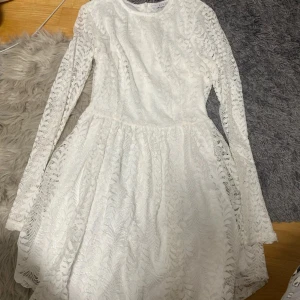 Vit spetsklänning från NLY Trend - Superfin vit kortklänning från NLY Trend i spets med långärmade ärmar och rund halsringning. Klänningen har ett vackert spetsmönster över hela och dragkedja i ryggen. Perfekt för student eller sommarens alla tillfällen!