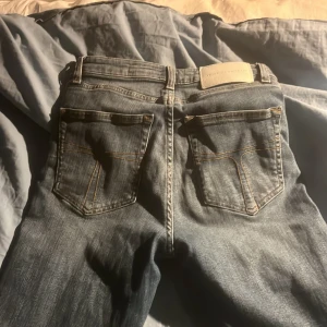 Blå jeans Shelly 28/30 - Snygga blå jeans från Shelly i klassisk femficksmodell med kontrastsömmar och normal passform. Jeansen har en lätt tvättad look och är tillverkade i bomullsmaterial. Perfekta för dig som gillar en enkel och stilren denimstil.