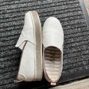 Vita sneakers - Snygga vita sneakers från River Island med ormmönstrad yta. Perfekta för dig som vill sticka ut lite extra. Använda ett par gånger men fortfarande i mycket bra skick.