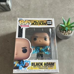 Funko Pop! Black Adam #1232 - Samlingsfigur Funko Pop! Black Adam #1232 från filmen Black Adam. Figuren är i originalförpackning, som är i gott skick med endast mindre slitage i hörnen. Perfekt för samlare eller fans av DC Comics och filmen Black Adam.