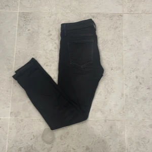 Svarta slim fit jeans Jack & Jones - Svarta slim fit jeans från Jack & Jones, modell Glenn. Klassisk femficksdesign med smal passform och normal midja. Jeansen är tillverkade i ett stretchigt bomullsmaterial som ger en bekväm känsla och snygg siluett.