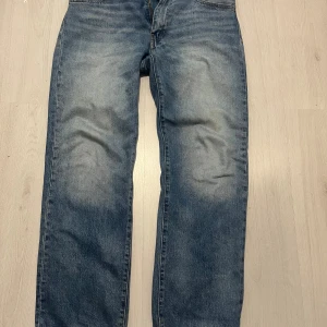 Levi's blå jeans  - Klassiska blå Levi's 555 jeans med rak passform och snyggt tvättad look. Jeansen har fem fickor, gylf med dragkedja och den ikoniska läderpatchen bak i midjan. Perfekta för dig som gillar en tidlös och avslappnad stil. Nypris 1200kr