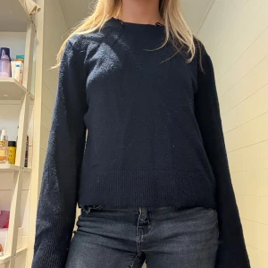 Mörkblå stickad tröja med vida ärmar - Mysig mörkblå stickad tröja med breda ribbade muddar vid ärm och nederkant. Fint skick. 