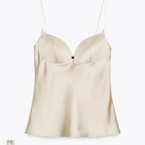 Champagnefärgad satin linnetopp - Säljer en helt ny champagnefärgad linnetopp i satin med tunna axelband och formade kupor. Lappen är kvar och är i storlek L!