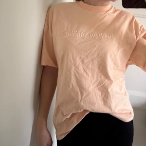 Persikofärgad t-shirt från  - Persikofärgad t-shirt med broderad text ”Keep on smiling” storlek xxs men oversized modell så passar xxs-s