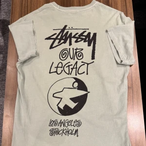 Stüssy x Our Legacy mintgrön t-shirt - Mintgrön t-shirt från Stüssy x Our Legacy med svart grafiskt tryck på både bröstet och ryggen. Trycket har coola handskrivna bokstäver och en stor grafisk symbol på ryggen. T-shirten har rund hals och korta ärmar, tillverkad i mjuk bomull. Size S, passar även M. Finns nån fläk men går nog bort i tvätt! 299kr Allt gott, Brur🫰🏽