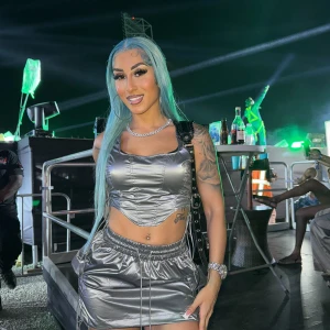 Silvrig kort kjol med matchande topp - Säljer en glansig silvrig kort kjol med elastisk midja och dragsko-detaljer på sidorna. Topp medföljer. Kjolen har en sportig vibe och är tillverkad i ett syntetmaterial som ger en futuristisk look. Perfekt för dig som vill sticka ut på nästa event! Org pris 600kr.