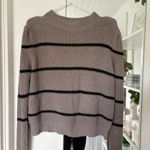 Randig stickad tröja i beige och svart - Säljer en chunky stickad tröja i beige med svarta horisontella ränder. Tröjan har en hög, ribbad halsringning och långa ärmar. Perfekt för lager-på-lager och chill vibes under kyliga dagar. Storlek xs ungefär💓