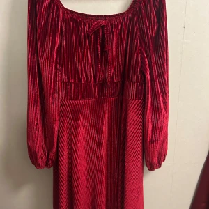 Röd sammetsklänning från SHEIN Curve - Superfin röd sammetsklänning från SHEIN Curve i storlek 2XL. Klänningen har långa ärmar, snyggt rynkad överdel och knytning vid halsen. Materialet är glansigt och mjukt med vertikala ränder som ger en cool effekt. Perfekt för dig som vill sticka ut med en färgstark look.
