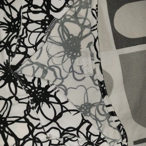 Vit och svart blommig topp ifrån Stockh LM - Säljer en vit och svart topp från Stockh LM i storlek M. Klänningen har ett coolt blommigt mönster och är ärmlös med en rak, kort passform. Perfekt för dig som gillar grafiska prints och vill sticka ut lite extra.