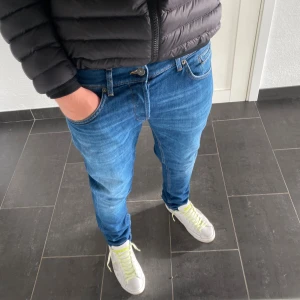 Dondup George  - Säljer ett par blå dondup George i klassisk denim och orangea sömmar. Modellen har slim passform och slim ben, perfekt för dig som gillar en stilren look. Jeansen har fem fickor och är tillverkade i mjukt bomullsmaterial.