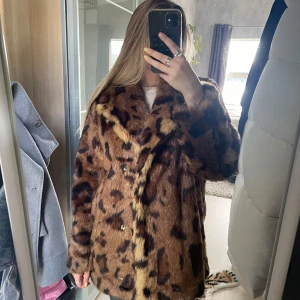 Leopardmönstrad pälsjacka - Säljer en fluffig och oversized pälsjacka med leopardmönster i bruna och svarta toner. Jackan har långa ärmar, bred krage och stängs med knappar framtill. Perfekt statement-plagg för dig som vill sticka ut och hålla dig varm under kyliga dagar.