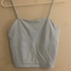 Ljusblå linnetopp med smala axelband - Säljer en enkel och stilren ljusblå linnetopp med smala axelband. Toppen har rak skärning och ärmlös design, perfekt för varma dagar. Materialet känns mjukt och lätt mot huden. Passar dig som gillar minimalistisk och fräsch stil.
