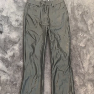 Svarta skinnbyxor - Snygga svarta byxor i skinnimitation från Amisu i storlek 32. De är högmidjade och för de som inte gillar det så kan man bara ha på sig en stickad kofta för att gömmma det.