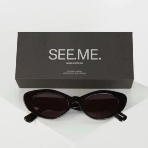 Svarta cat eye-solglasögon SEE.ME - Snygga svarta solglasögon från SEE.ME med trendig cat eye-form. Glasögonen har blanka svarta bågar och mörka glas, perfekta för en cool och stilren look. Kommer med originalförpackning.