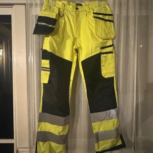 Gula arbetsbyxor Bluewear strl 50 - Arbetsbyxor från Bluewear i starkt gul färg med svarta och grå detaljer. Flera praktiska fickor, reflexband runt benen. Perfekta för dig som vill synas och ha bra funktion på jobbet. Inte använda inom arbete, fick dom när jag fyllde 16 och har bara legat i min garderob☺️