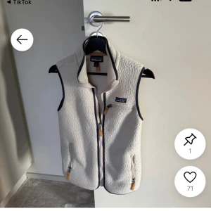 Beige fleeceväst från Patagonia - Snygg beige fleeceväst från Patagonia med hög krage och dragkedja framtill. Västen har två fickor med dragkedja och mörka kantdetaljer. Perfekt för lager-på-lager och outdoor vibes.
