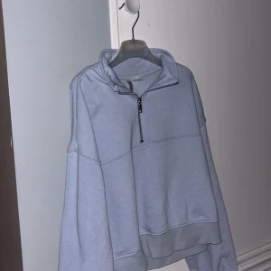 Ljusgrå half zip hoodie från Divided - Ljusgrå hoodie från Divided med halv dragkedja och hög krage. Oversized fit med långa ärmar och breda muddar. Perfekt för chill dagar och enkel att matcha med jeans eller mjukisbyxor.