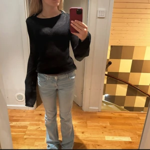 Svart stickad tröja med vida ärmar - Svart stickad tröja med snygga vida ärmar och rund hals. Perfekt att styla med jeans eller kjol för en trendig look. Nästan aldrig använd.           Storlek S