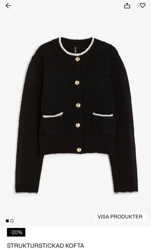 Svart strukturststickad kofta med guldknappar - Svart kofta från Gina Tricot med strukturststickat material och kontrastdetaljer i vitt vid krage, fickor och ärmslut. Guldiga knappar framtill ger en lyxig vibe. Rund hals och två fickor framtill. Perfekt för dig som gillar klassisk men trendig stil.