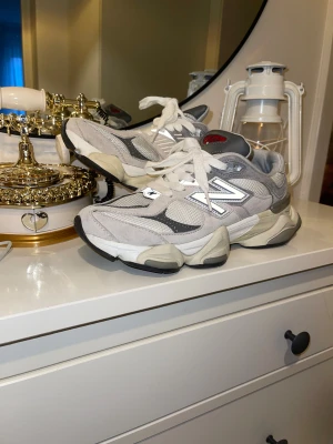 Grå New Balance sneakers med chunky sula - Säljer ett par grå och vita New Balance sneakers med chunky plattformssula. Skorna har mesh och mocka-paneler, snörning och den klassiska N-loggan på sidan. Perfekt för dig som gillar streetstyle och vill ha bekväma sneakers med cool design.