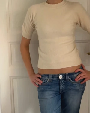 Beige trekvartsärmad kashmirtröja  - Supermjuk och lyxig beige topp i kashmir från H&M. Modellen är croppad med korta ärmar och rund halsringning. Perfekt för dig som gillar stilrena och enkla plagg med exklusiv känsla. Passformen är normal och färgen är ljusbeige.