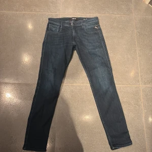Replay Anbass jeans  - Snygga Replay Anbass jeans i mörkblå tvätt med klassisk femficksdesign och slim passform. Jeansen har normal midja, dragkedja och knappstängning samt diskreta Replay-detaljer vid fickorna. Perfekt för dig som gillar stilrena och moderna jeans. Storleken är 30/32 och är använda ett vid ett fåtal tillfällen, mitt pris är 449 vilket är ett väldigt bra pris!! Skriv vid vilken fråga som helst!
