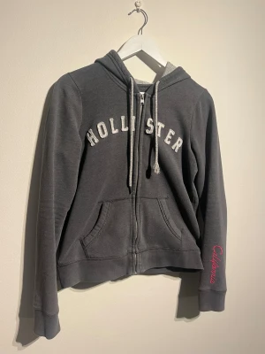 Hollister Zip Hoodie - Hej! Säljer nu denna väldigt snygga Hollister Zip Hoodien Storlek XS   Färg: Grå & Vit Skick: 8/10 Väl använd men ändå i bra skick  Skickas spårbart eller hämtas upp efter överenskommelse. Vid intresse – hör gärna av dig.  Skriv vid frågor eller ifall du vill ha fler bilder:) 