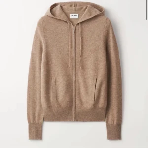 Beige/brun hoodie i kashmir från Soft Goat - Snygg beige/brun hoodie från Soft Goat i kashmir. Tröjan har huva med snörning, dragkedja framtill och ribbade muddar. 