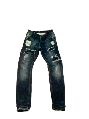 Adrian Hamond jeans - Ett par riktigt unika och skit snygga jeans med många snygga detaljer och slitningar. Jeansen är i bra skick och i storlek 30 men passar mer som 31 med midje måttet 41cm