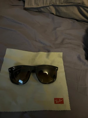 Svarta solglasögon från Ray-Ban (köpte nya för 1900) - Snygga svarta solglasögon från Ray-Ban med klassisk Wayfarer-inspirerad form. Glasen är mörka med en lätt toning och bågarna är i blank svart plast. Perfekta för att lyfta din stil i solen.