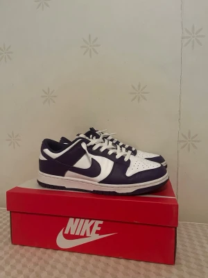 Nike Dunk Low  - Nike Dunk Low sneakers i vit och mörklila färg. Bra skick. Använda fåtal gånger. 
