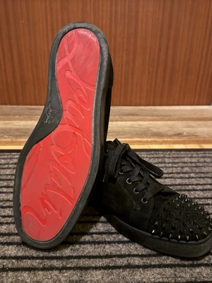 Louboutin Junior med spikar - Äkta svarta Louboutin Juniors med spikar. Köpta från Manér Closet. Mycket fint skick förutom det ni ser på bilderna och att en spik saknas på höger sko. Bara skor medföljer.
