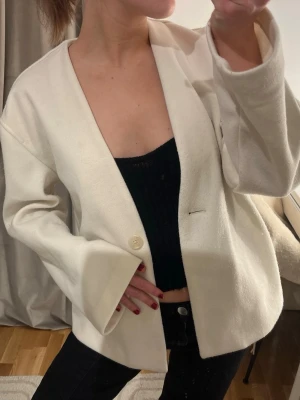 Vit jacka kavaj   - Stilren vit kavaj i oversized modell med en enkel knapp framtill. Kavajen har lång ärm och rak passform, perfekt att slänga över en topp för en clean look. Materialet känns mjukt och har en lätt struktur.