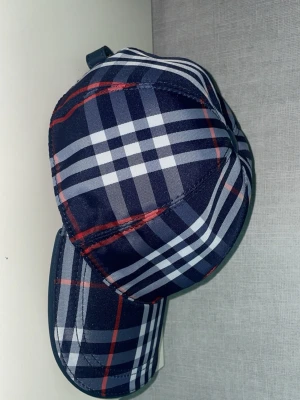 mörkblå rutig Burberry keps  - Stilren burberry keps, verkligen ett kap inför sommaren ifall man vill känna sig lite mer unik. Pris kan diskuteras.