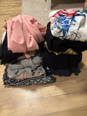 Klädpaket med blandade plagg - Säljer ett klädpaket med flera olika plagg, bland annat en rosa kavaj, en topp med färgglatt blommönster, stickade tröjor, gråa och beige byxor samt ett par mönstrade byxor i svartvitt. Perfekt för dig som vill förnya garderoben med olika stilar och färger.Lite blandade kläder i olika storlekar, med kommer  Blus storlek m Jeans storlek L Tröja storlek m Stickad tröja storlek m Tröja storlek l  Kavaj storlek m  Klänning storlek xl  Shorts storlek l  Tröja storlek m Kofta storlek l  Tröja storlek 