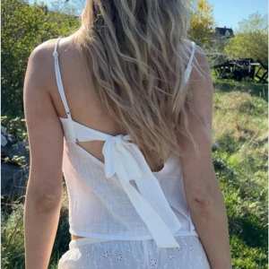 Vit linnetopp med rosett i ryggen - Superfin vit linnetopp med tunna axelband och en stor rosett i ryggen. Jättefin nu till vår och sommar🍓🌸