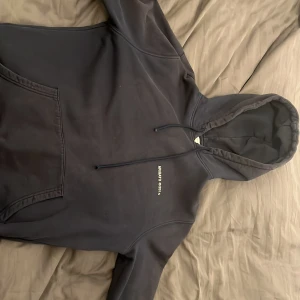 Svart hoodie från Axel Arigato. Storlek från halssömen ner till kanten 57cm,armlängd62cm och bredd 51cm - Svart hoodie med vit text 'ARIGATO ©2014' på ryggen och mindre tryck på bröstet. Klassisk känguruficka framtill och justerbar huva med dragsko. Mjuk bomullskänsla och avslappnad passform, perfekt för en streetwear-look.